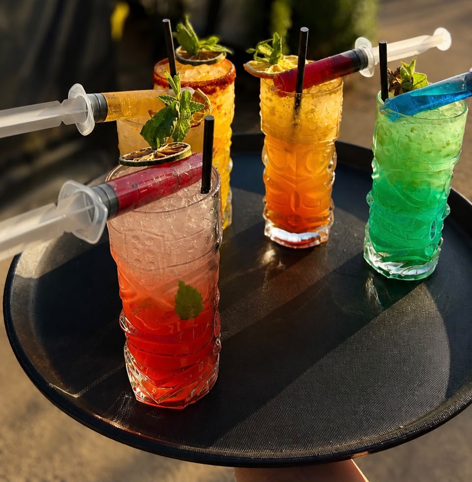Bandeja de cócteles con jeringa de licor en Bravo's Restobar