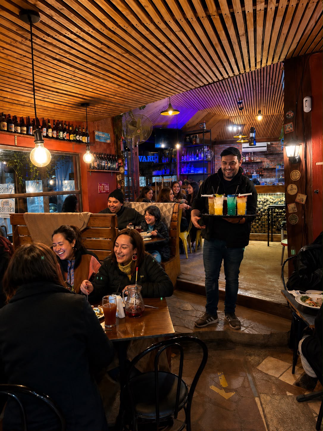 Mesero de Bravo's Restobar sirviendo cócteles con jeringa, con comensales de fondo