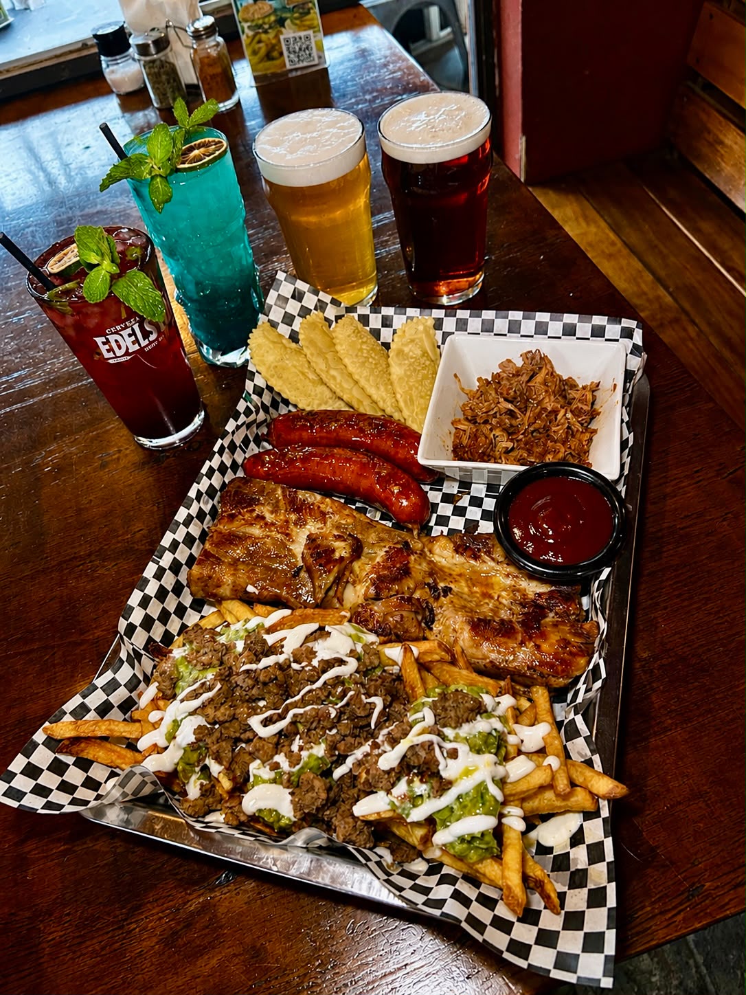 Tabla de especialidades Bravo's Restobar con costillas, carne, chorizos, papas y tragos