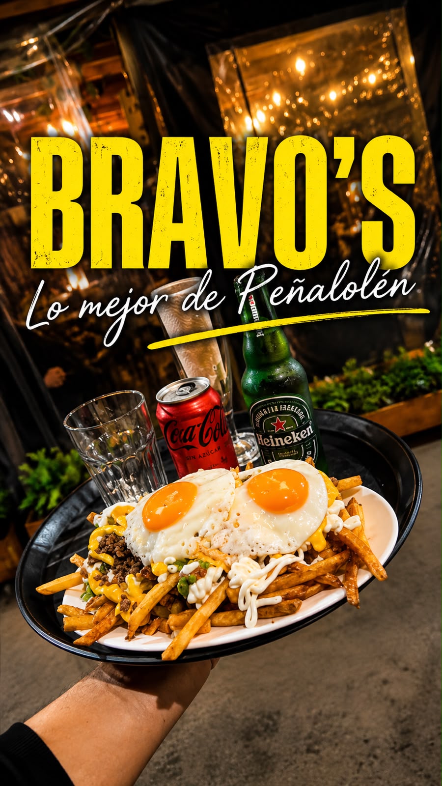 Papas cargadas con carne, huevos fritos y bebidas, con el letrero Bravo's - Lo mejor de Peñalolén de fondo, para compartir en Bravo's Restobar