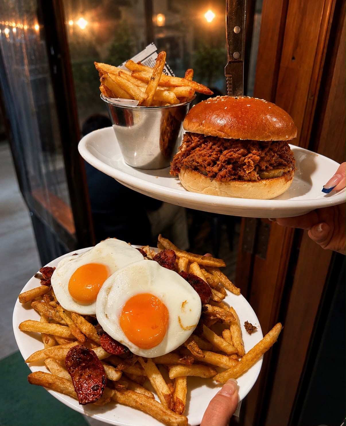 Sandwich de carne desmechada con papas fritas y plato de huevos fritos con chorizo
