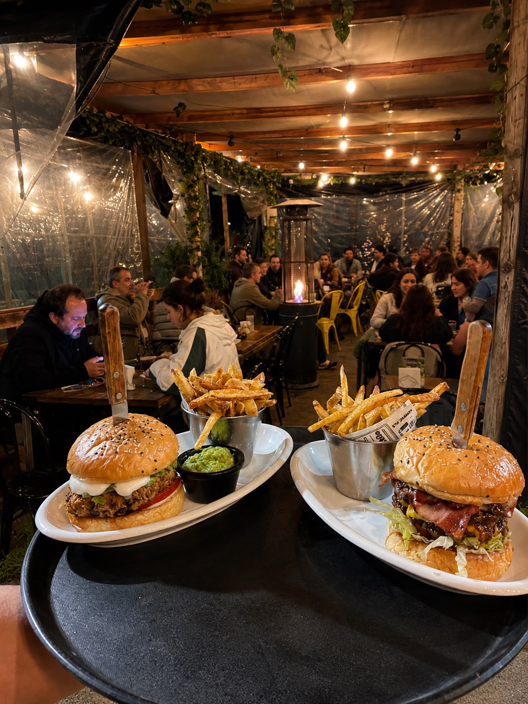 Hamburguesas de Bravo's Restobar en bandeja, con la terraza y clientes del local de fondo